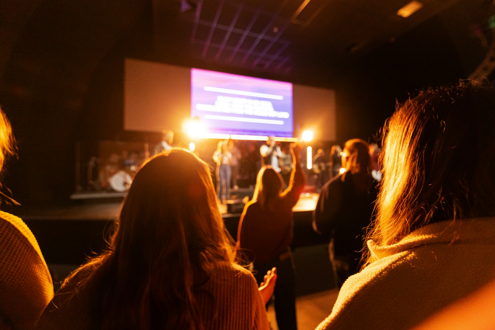 An audience seated in front of an illuminated stage